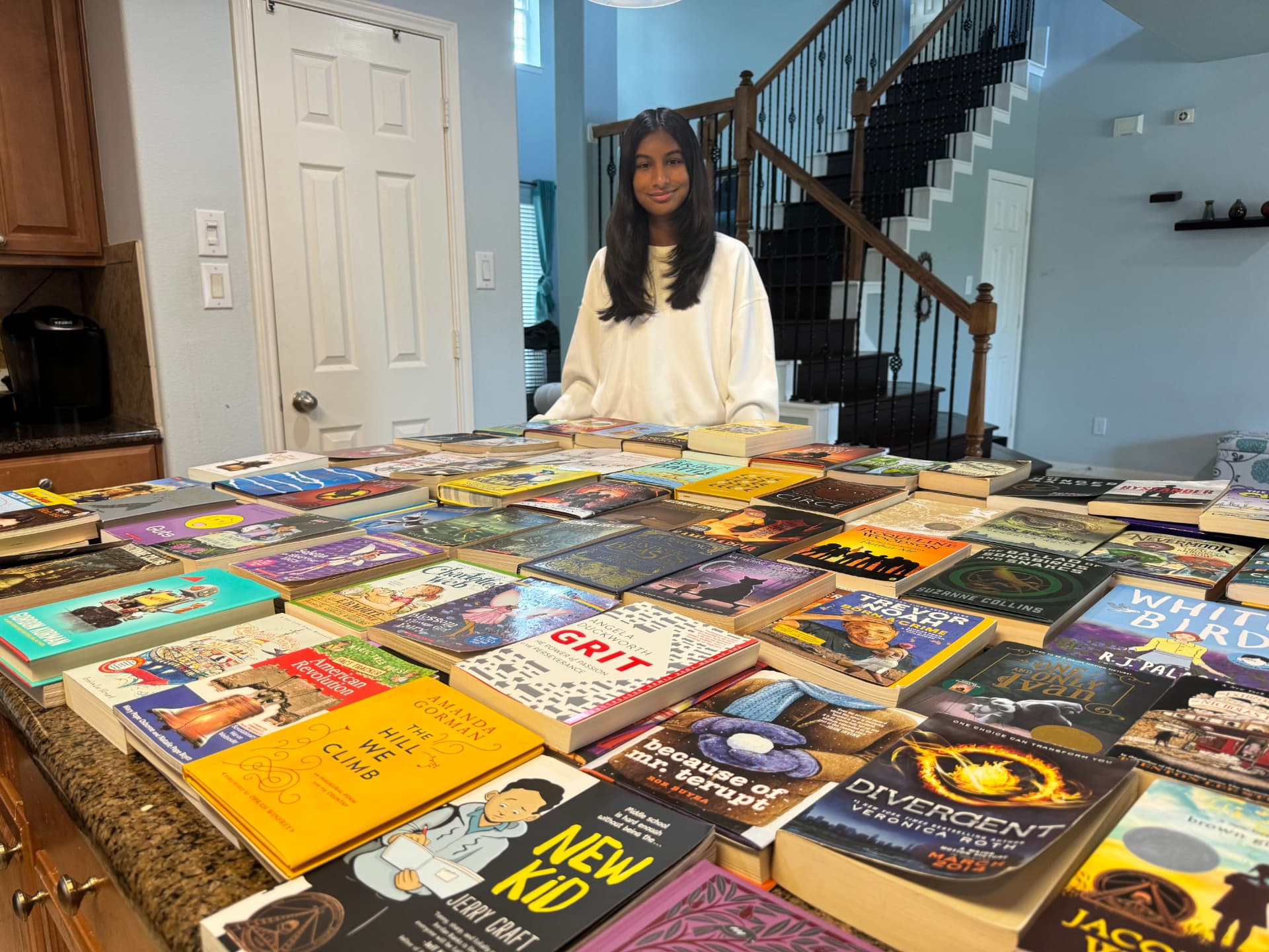 Hundreds of donated books laid out on a table before distribution